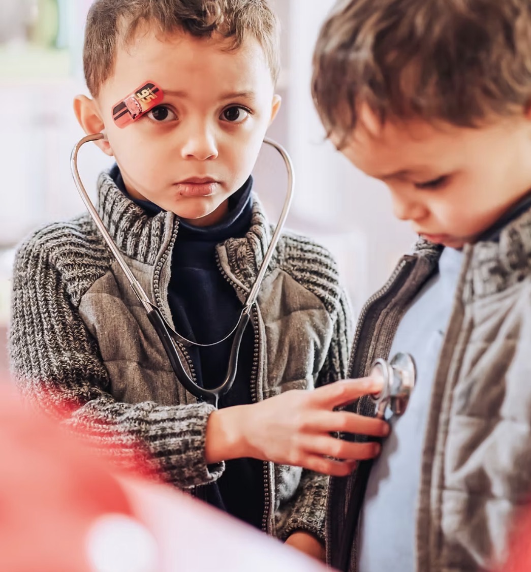 Two boys playing doctor with a stethoscope during imaginative play