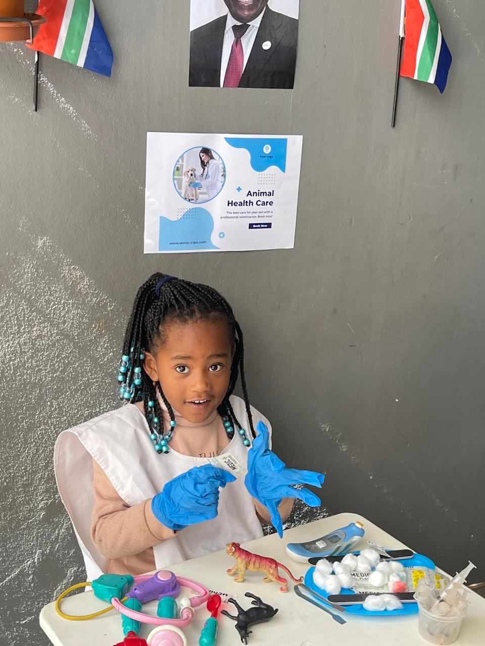 A girl wearing gloves and an apron playing vet with toy animals and medical kit