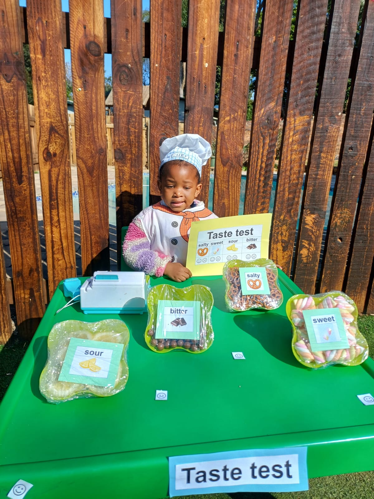 A child in a chef's hat exploring a salty, sweet, sour and bitter taste test