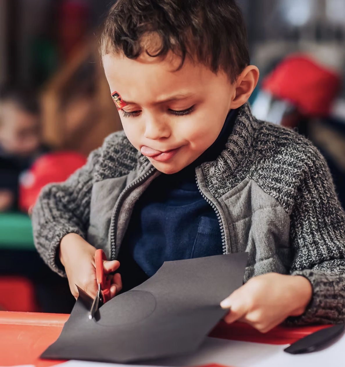 A boy carefully cutting paper with scissors during a craft activity